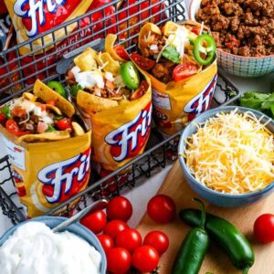 walking tacos in fritos bags surrounded by different taco toppings