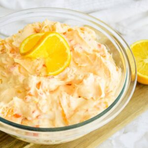 closeup of bowl of mandarin orange jello salad on a wooden cutting board