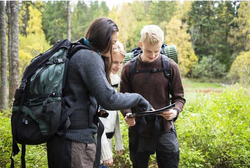 Three people looking at a map in the woods.