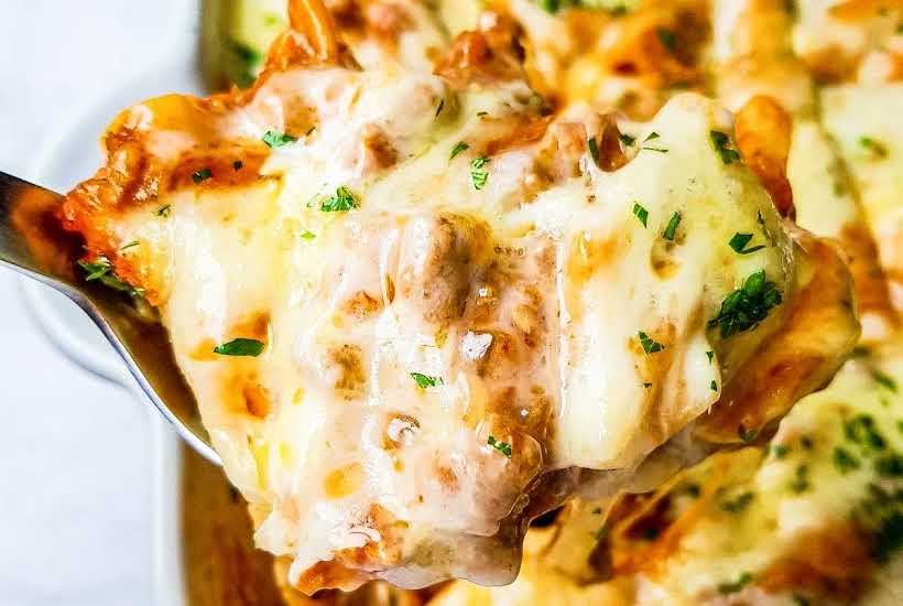 Close up view of a slice of pasta casserole on a large spoon.