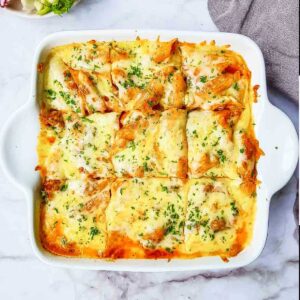 Cheesy pasta casserole in a white square dish.