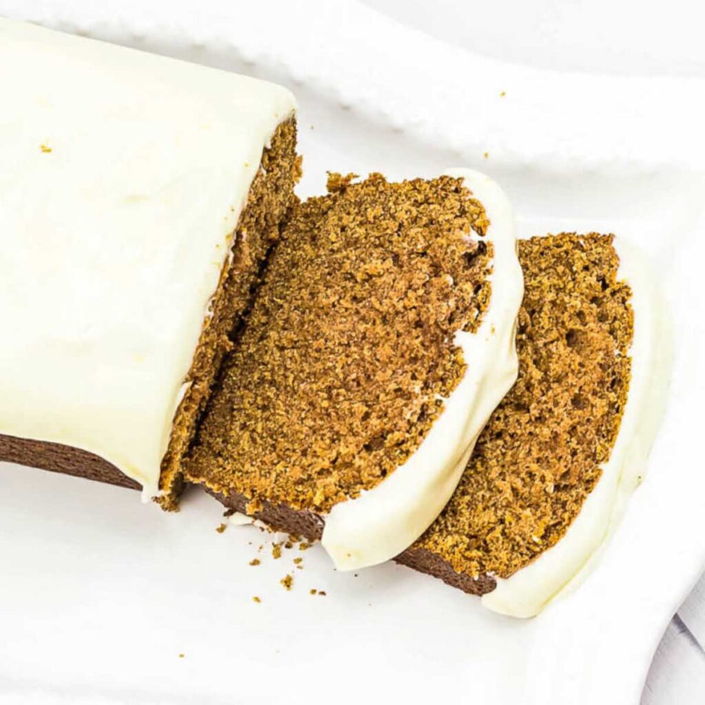 Top view of a sliced Starbucks gingerbread loaf on a white platter.