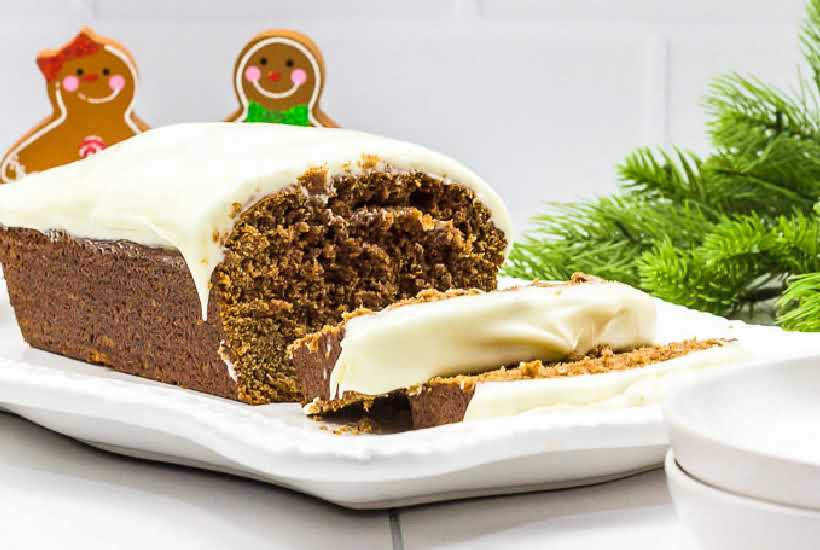 Front view of copycat Starbucks gingerbread loaf with slices cut and gingerbread men in the background.