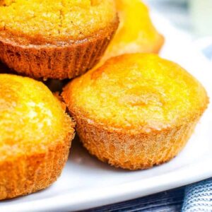 Cornbread muffins stacked on a white platter.