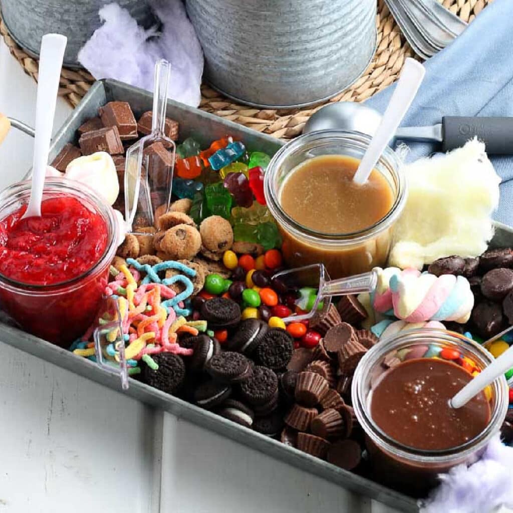 Metal serving tray filled with ice cream sauces and toppings.