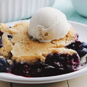 Close up of a slice of berry cobbler dessert topped with ice cream.