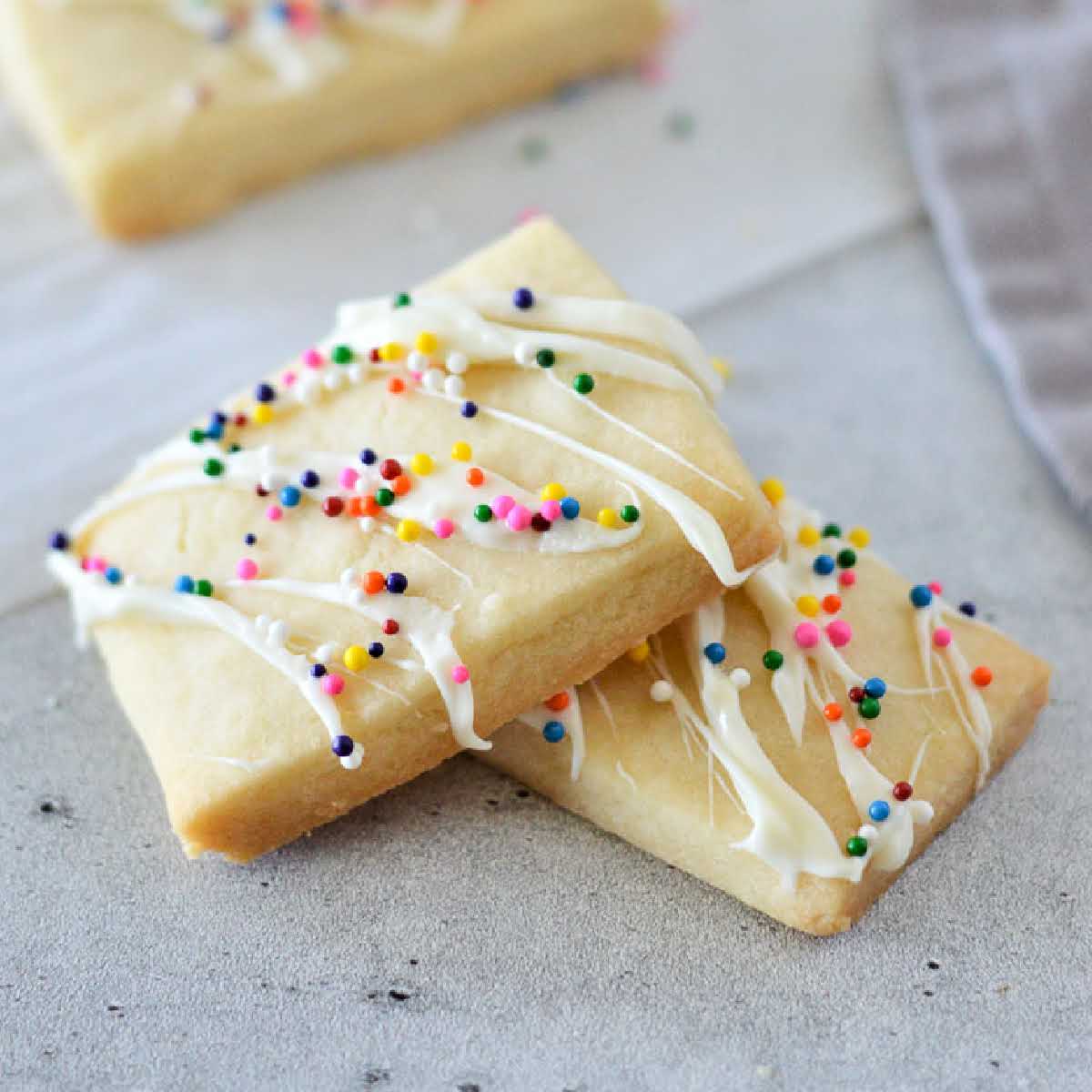 Two eggless butter cookies stacked on top of each other with frosting and sprinkles on top.