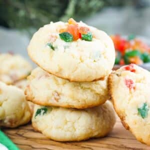 Cake mix fruitcake cookies stacked on a wooden cutting board.