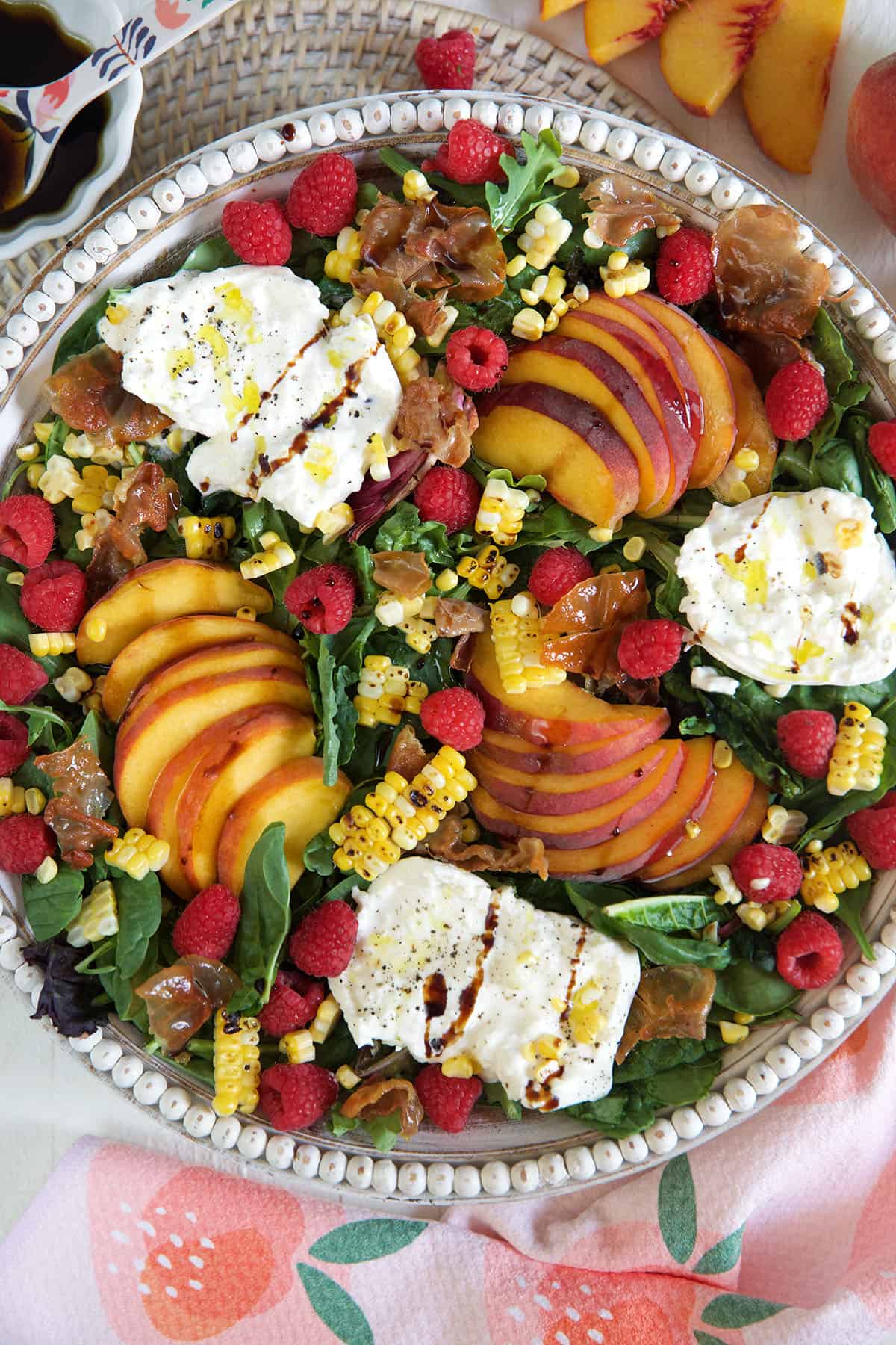 Salad made with peaches and burrata cheese with raspberries.