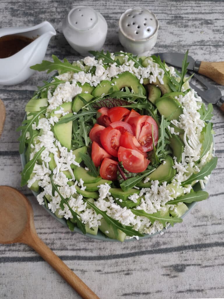A spring salad with arugula, cheese and tomato chunks.