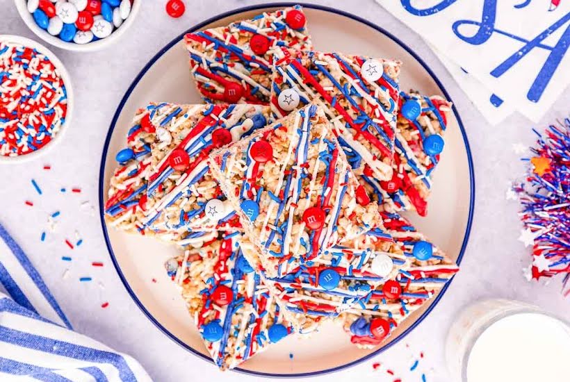 Marshmallow rice cereal squares decorated in a patriotic theme on a white plate.
