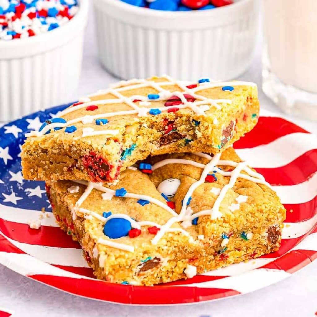 Two squares of red white and blue M&M cookie bars on a flag plate.
