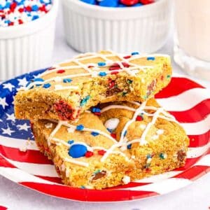 Two squares of red white and blue M&M cookie bars on a flag plate.