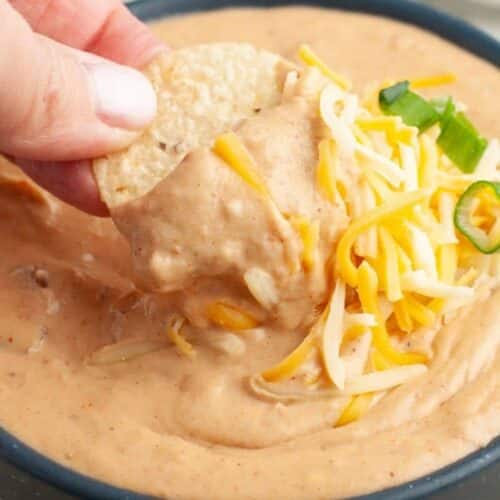 a bowl of bean dip with a chip.