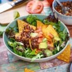 Black bean taco salad with tortilla chips, lettuce and avocado.