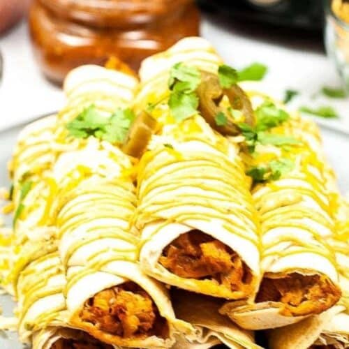 A plate of taquitos with cheese over top.