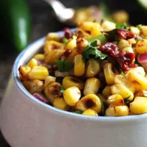 A bowl of salsa made of chipotle pepper and corn.