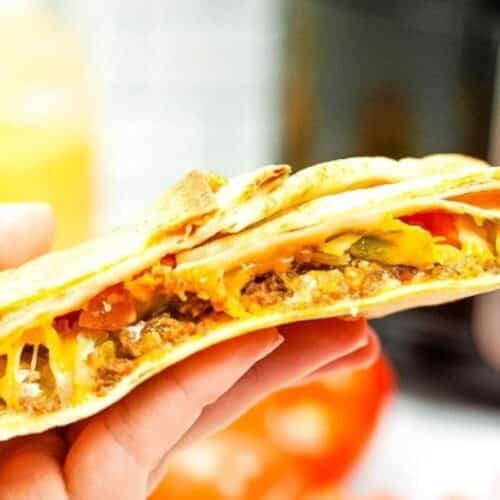 A copycat crunch wrap supreme being held in a hand.