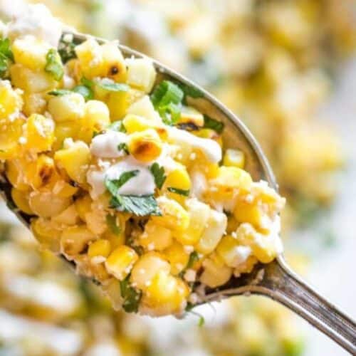 a spoon of corn salad with cheese and creamy dressing.