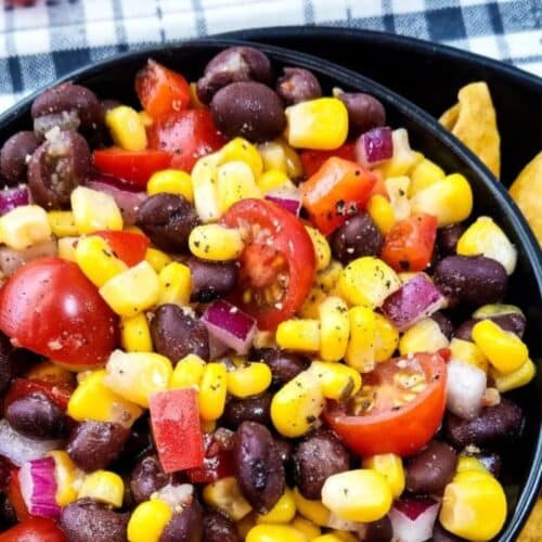 a bowl of black beans, corn, tomato and Italian dressing mixed into a salad.