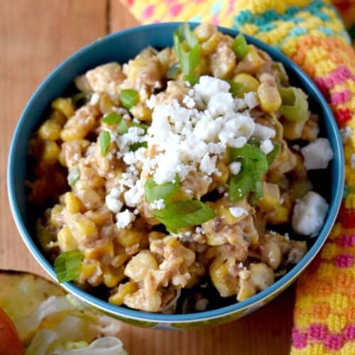 a bowl of corn salad with cojito cheese and a creamy dressing.