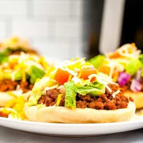 Three flatbread tacos on a plate with all of the toppings.