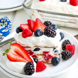 Slice of fresh berry icebox cake on a white plate with pan in the background.