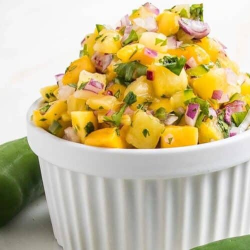 A white bowl filled with pineapple mango salsa.