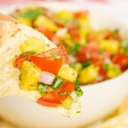 A chip lifting salsa from a bowl