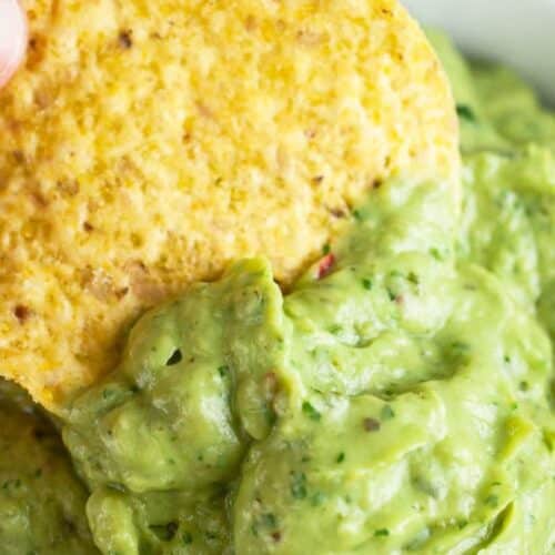 A bowl of avocado poblano sauce with a tortilla chip.