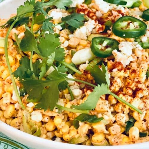 A bowl of salad made of corn, cheese and creamy street corn dressing.