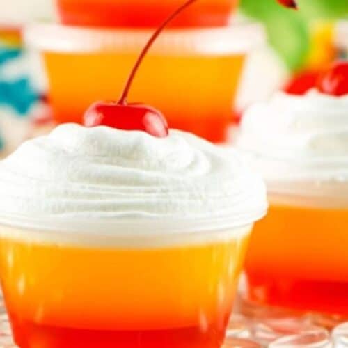 Layered jello shots with whipped cream on top.