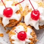 Three scoops of fried ice cream on a plate with whipped cream and cherries.