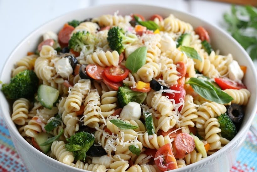 Closeup of bowl of pasta salad with fresh vegetables and cheese.