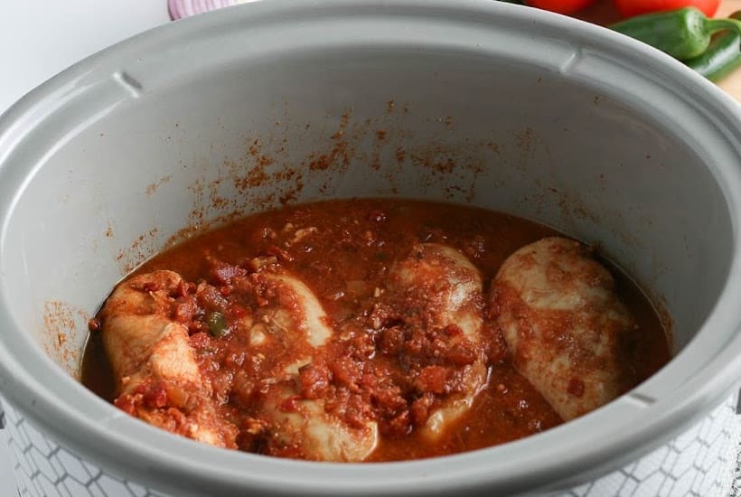 Crockpot filled with cooked chicken and salsa.