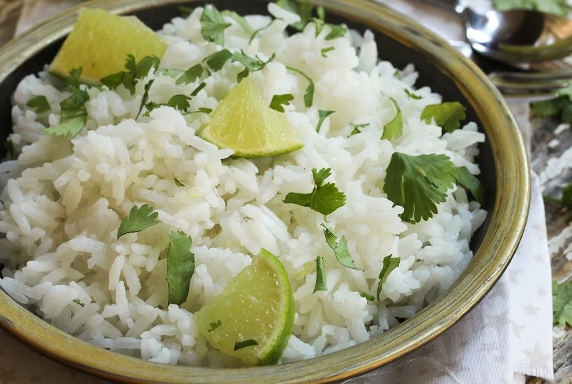 Bowl filled with cilantro rice with lime wedges.