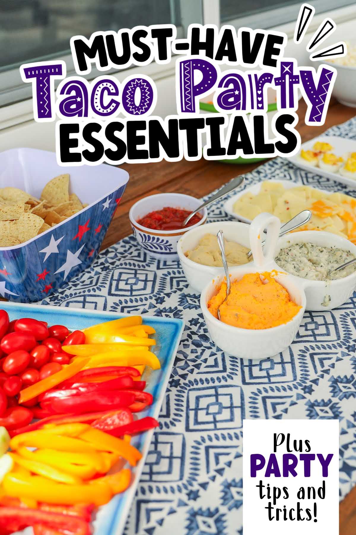 Dips, chips and sliced vegetables on a blue and white tablecloth with text overlay.