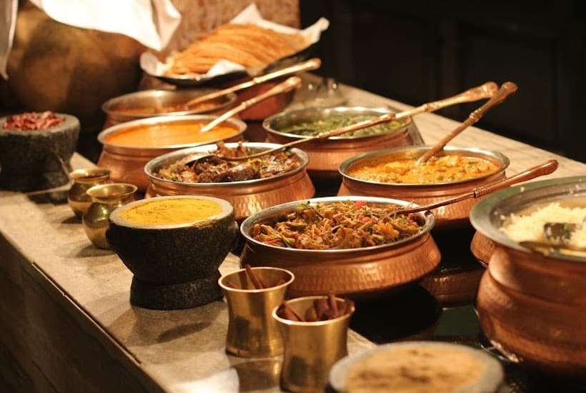 Table filled with serving dishes filled with taco bar food.