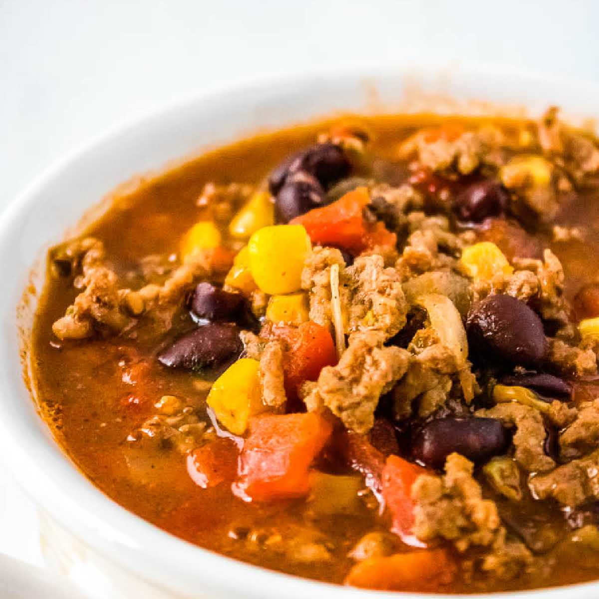 Closeup view of a bowl of taco soup with ground beef, black beans, tomatoes and corn.