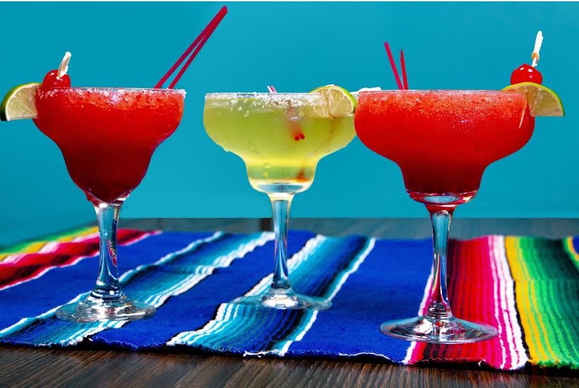 Three cocktails on a colorful Mexican runner.