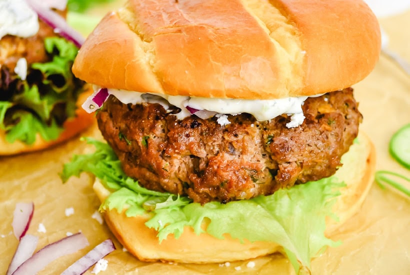 Beef patty with creamy cucumber sauce on a bun.