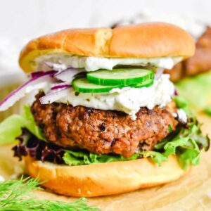 Burger topped with tzatziki sauce, cucumbers and red onion.