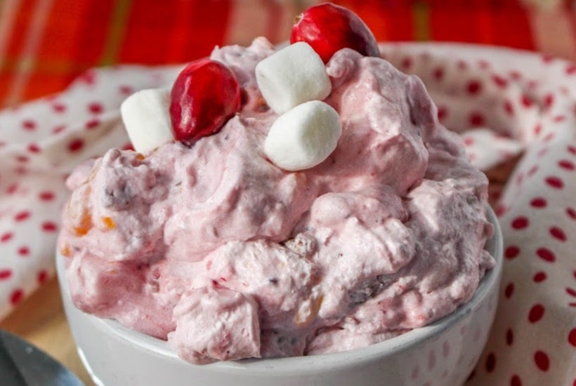 Closeup of a bowl of fluff salad with cranberries in a white bowl.