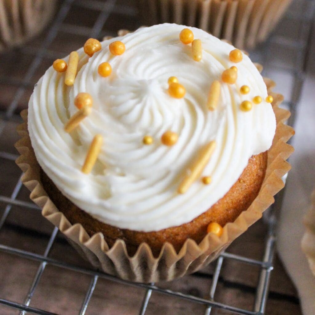 Closeup view of pumpkin cupcake with brown butter frosting and sprinkles.