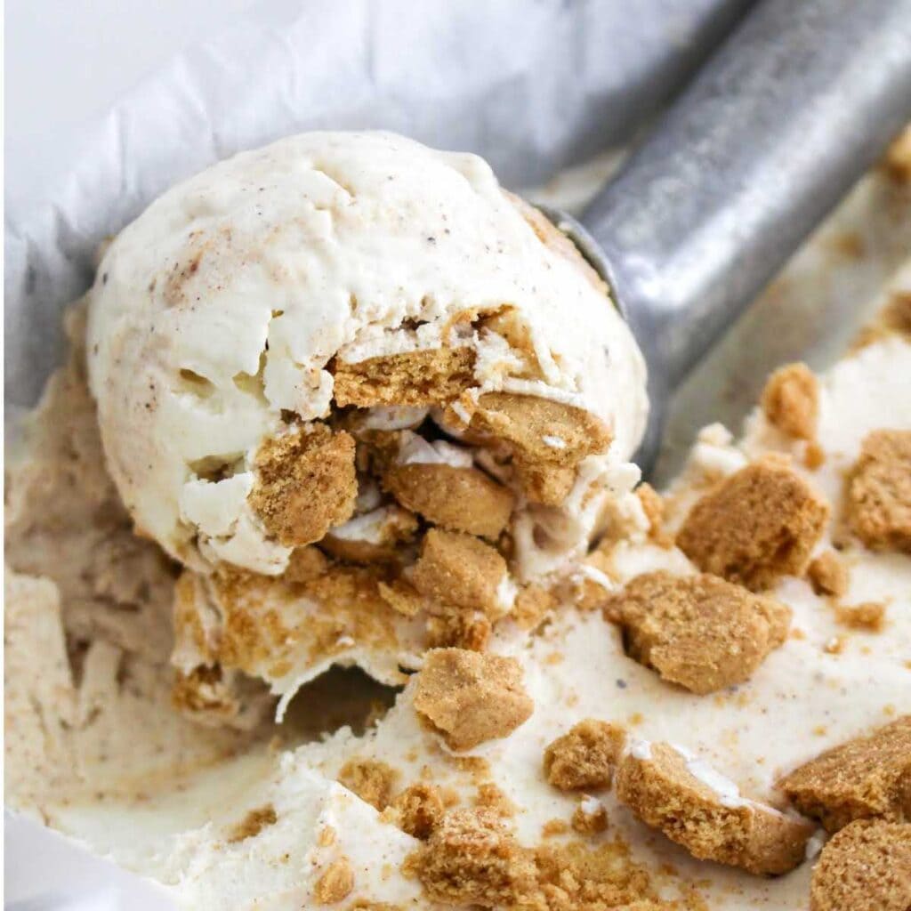 Closeup view of scooping out no churn gingerbread ice cream garnished with crushed gingerbread cookies.