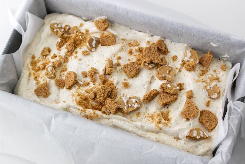 A loaf pan filled with homemade ice cream garnished with crushed gingerbread cookies.