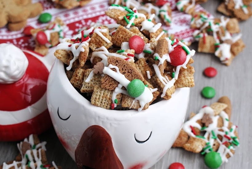 Decorative bowl filled with gingerbread chex mix surrounded by more mix.